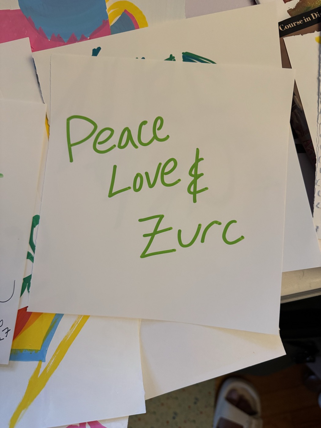 Peace Love and Zurc handwritten in green marker on a white square